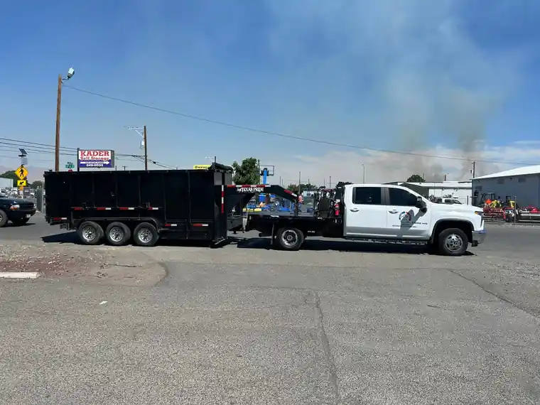 Our white pickup with the logo on the door, towing a tri-axle dump trailer.
