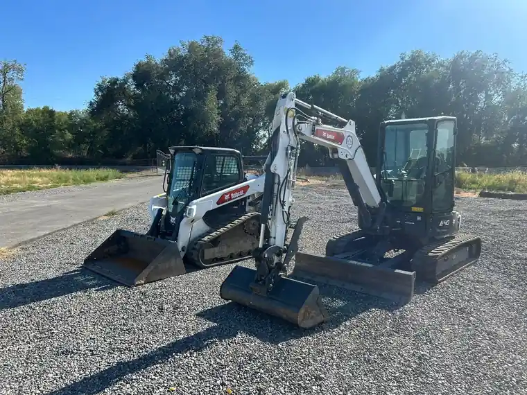 Our excavator and skid steer parked on gravel.