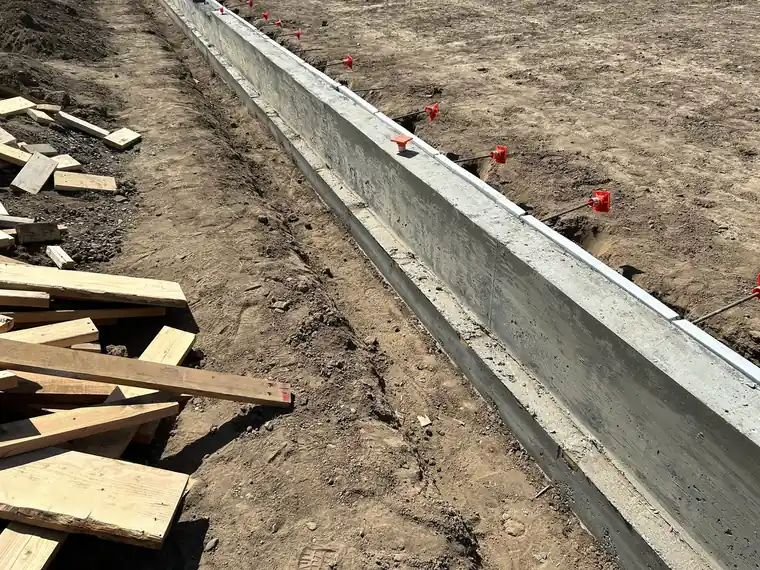 Poured concrete footing and stem wall with form stakes.