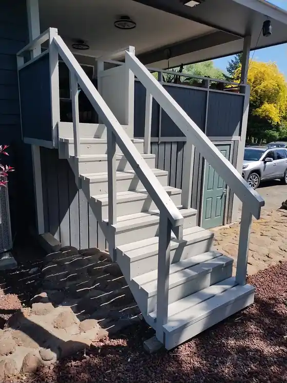 New grey exterior stair and deck on a blue-sided house.