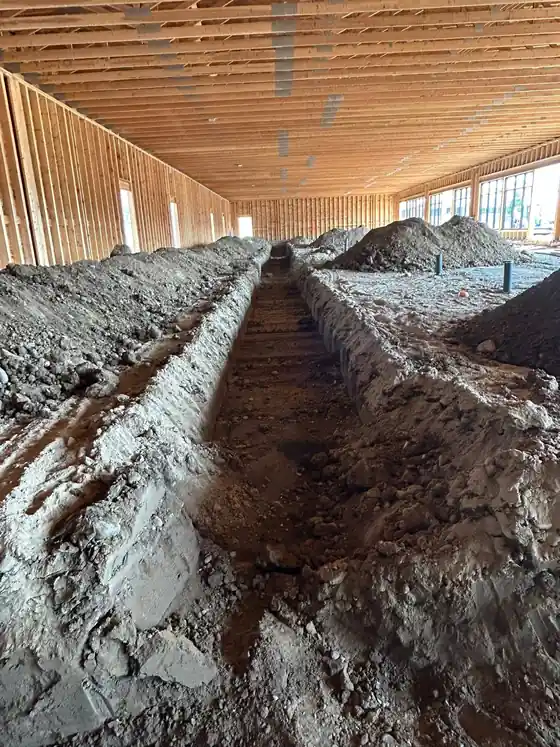 A trench dug inside a framed building.