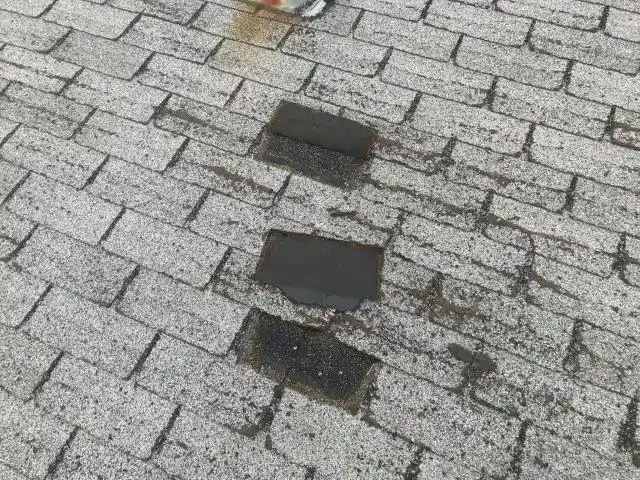 Asphalt shingle roof with patched sections after a repair