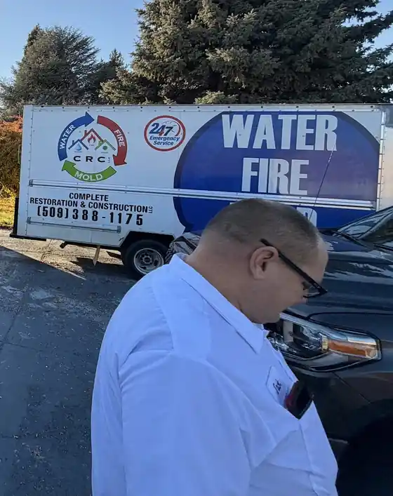 Our WATER FIRE box truck, lettered 24/7 Emergency Service, with a crew member beside it.