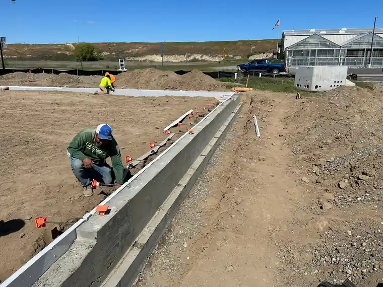 A worker kneeling at the footing forms.