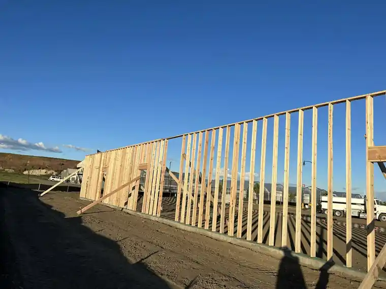 Stud wall framing against a blue sky.